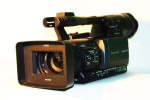 **Alt Text:** Close-up image of a professional video camera with a lens prominently labeled "Leica."