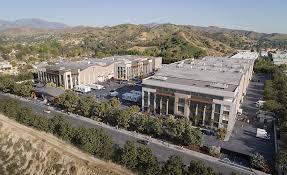 An aerial view of a large building complex with parking lots and surrounding hills.