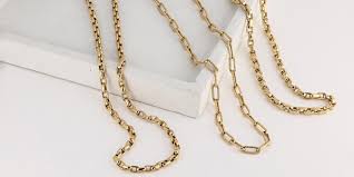 Gold chains with rectangular links arranged on a white surface.