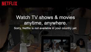 **Alt text:** The image shows a Netflix message stating, "Watch TV shows & movies anytime, anywhere. Sorry, Netflix is not available in your country yet," against a blurred background of a cafe setting with a tablet.
