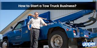 A man stands confidently next to a blue tow truck with the text "How to Start a Tow Truck Business?" above him.
