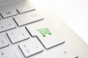 A close-up of a keyboard with a key featuring a green shopping cart icon.