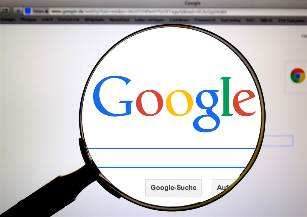 **Alt text:** A magnifying glass enlarges the Google logo on a computer screen displaying a web browser.