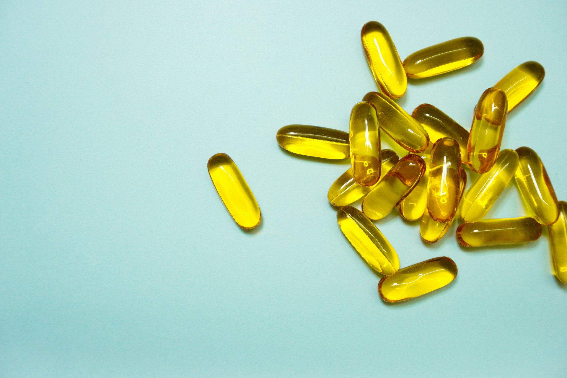 **Alt text:** A pile of yellow translucent capsules on a light blue background, with one capsule separated from the group.