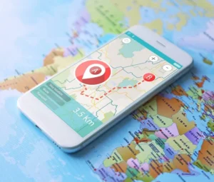 **Alt Text:** A smartphone displaying a navigation app with directional markers and a route plan is resting on a world map.