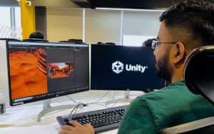 **Alt Text:** A person working on a video game project using Unity software, displayed on dual monitors.