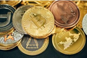 **Alt text:** A variety of cryptocurrency coins, including prominent Bitcoin coins, are stacked together.