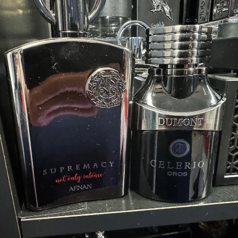 **Alt text:** Two bottles of cologne, one labeled "Supremacy, not only intense, Afnan" and the other "Dumont Celerio Oros," displayed on a shelf.