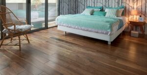 A cozy bedroom with a large bed adorned with teal bedding, a wooden chair, and a stylish wood floor.