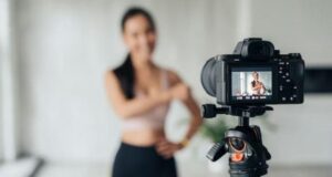 **Alt text:** A camera on a tripod focuses on a woman posing, captured on the camera's display screen.