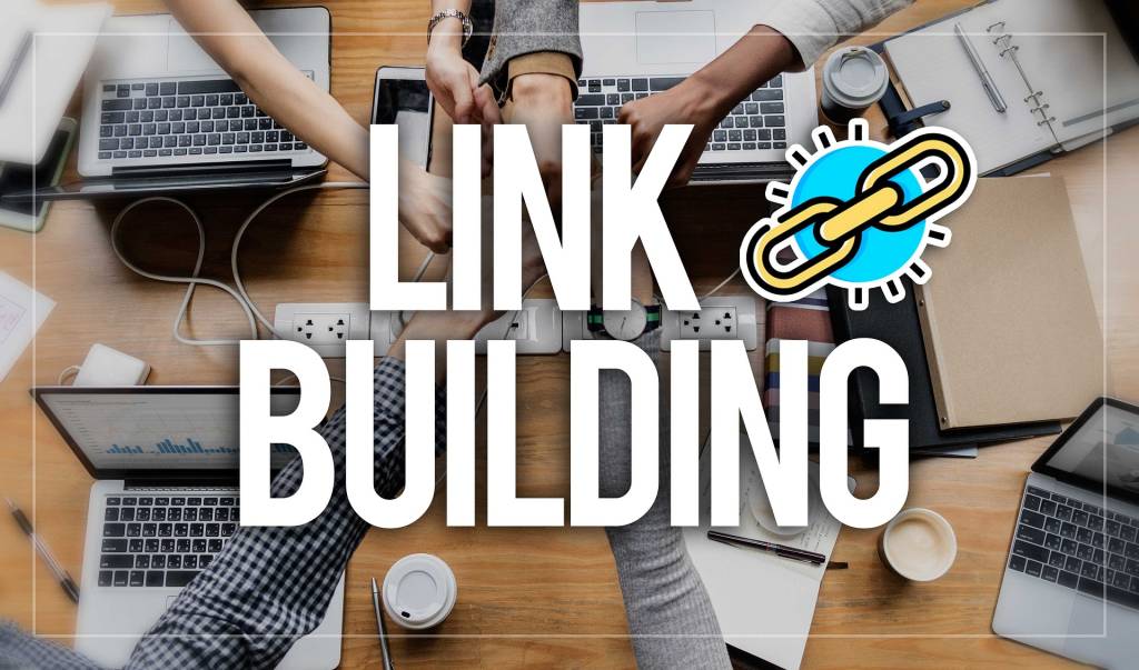 **Alt Text:** A group of people touching hands over a table with laptops and documents, with the words "Link Building" prominently displayed.