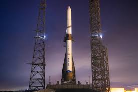**Alt text:** A large rocket stands upright on a launch pad at dusk, flanked by two towers under a deep blue sky.