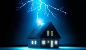 **Alt text:** A small house with lit windows is struck by a bright bolt of lightning in a dark setting.