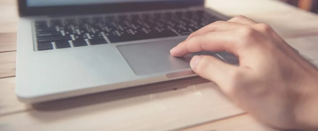 A person's hand using the touchpad of a laptop.