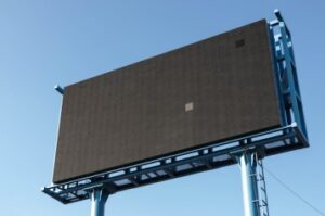 **Alt text:** A large, empty black billboard set against a clear blue sky.