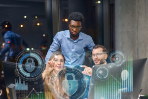 Alt text: Three people in an office setting are analyzing digital security graphics displayed on a transparent screen.