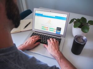 Alt text: A person is using a laptop displaying a website performance analysis, with a notebook, pen, and a plant nearby on the table.